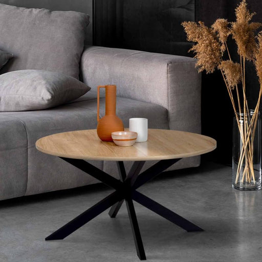 Wooden top coffee table with black feet with vase and grey sofa on the back