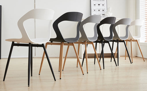 Group of six white chairs with intricate carved designs, arranged neatly for a minimalist dining room aesthetic