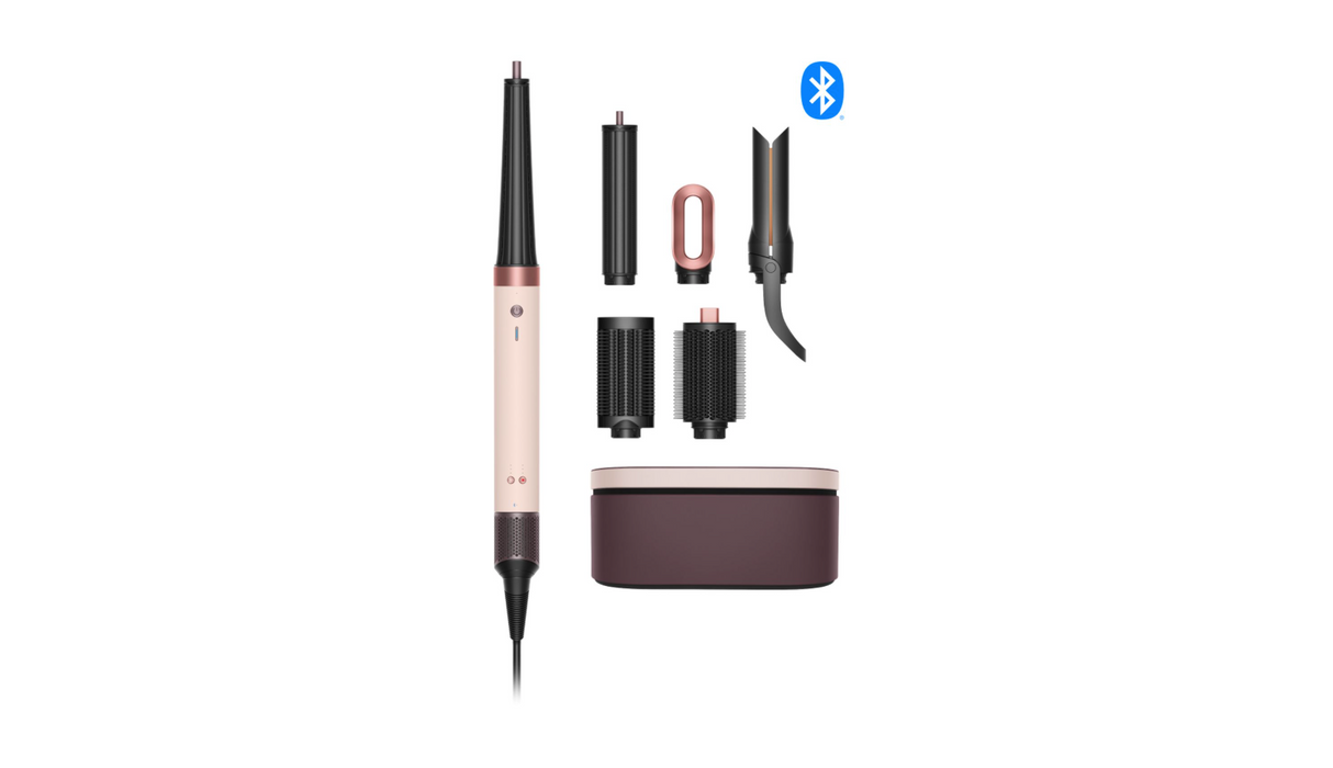 A hair styling tool set on a white background, featuring a rose gold and black wand-style device, several interchangeable attachments, a dark brown charging case, and a small blue Bluetooth symbol.