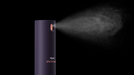 A dark purple cylindrical Dyson Chill to 95% humidifier spray bottle emitting a fine white mist against a solid black background.