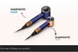 Two supersonic hair dryer models shown on a light beige background: the larger 'supersonic nural' in dark blue with copper accents, and the smaller 'supersonic Travel' in dark blue with copper accents. Text and arrows point to each model, with a black banner at the bottom reading '32% smaller.