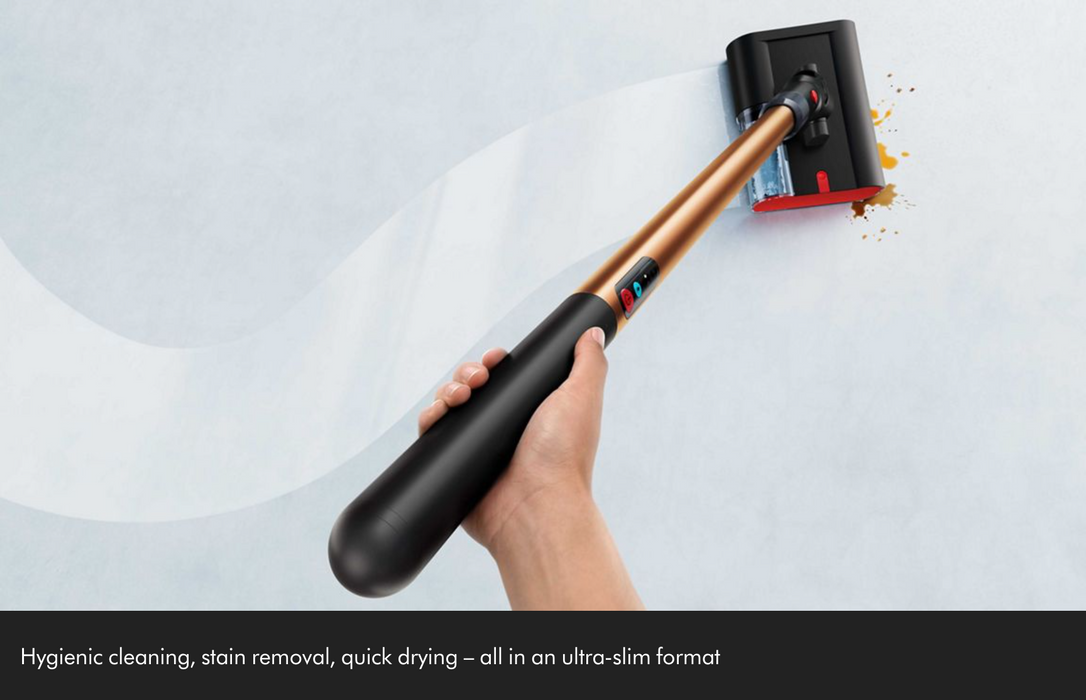 A hand holding a cordless stick vacuum cleaner with a metallic copper shaft and black handle, shown cleaning a light gray surface with a white mist effect. A black banner at the bottom contains marketing text.